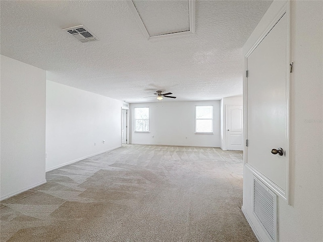 empty room with ceiling fan, light colored carpet, and a textured ceiling