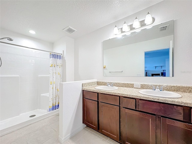 bathroom with tile patterned flooring, vanity, curtained shower, and a textured ceiling