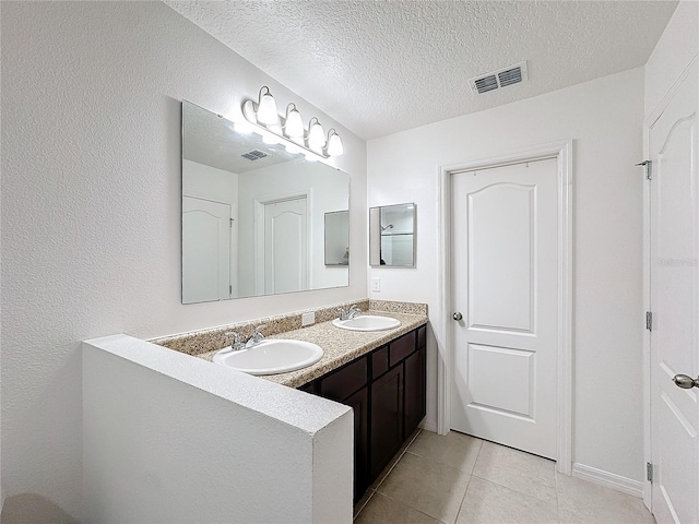 bathroom with vanity, a textured ceiling, and tile patterned floors