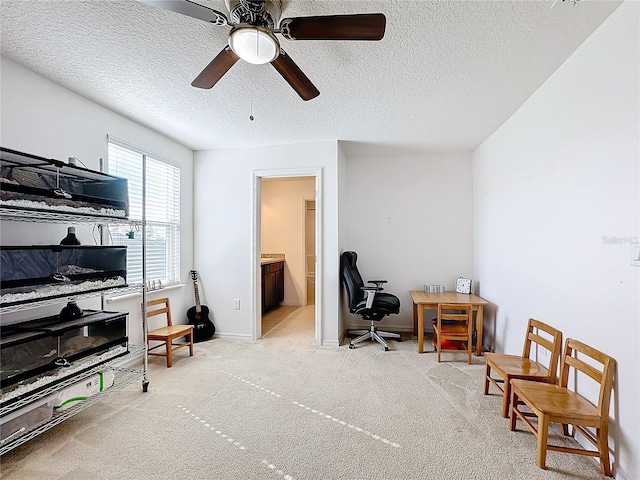 home office featuring a textured ceiling, ceiling fan, and light carpet