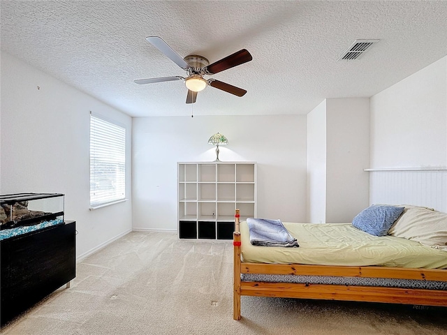 carpeted bedroom featuring ceiling fan and a textured ceiling