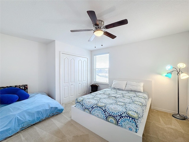 bedroom featuring ceiling fan, light colored carpet, and a closet