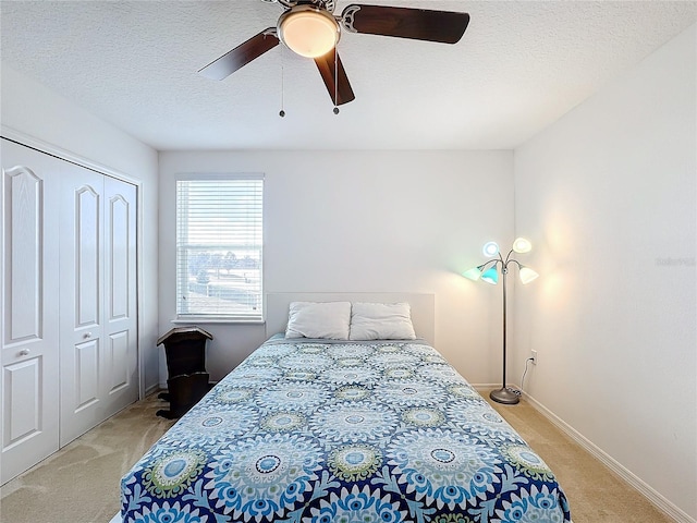 carpeted bedroom with ceiling fan, a closet, and a textured ceiling