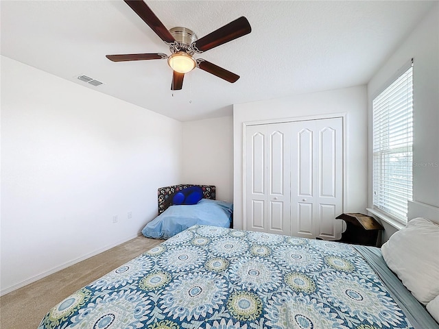 carpeted bedroom featuring ceiling fan and a closet