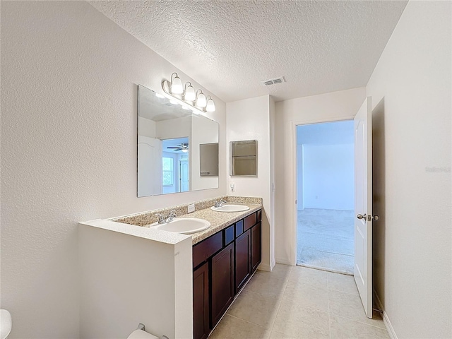 bathroom featuring tile patterned floors, vanity, ceiling fan, and a textured ceiling