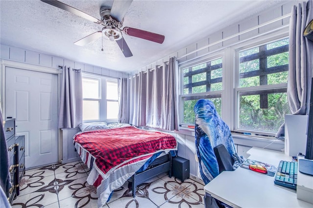 tiled bedroom with ceiling fan and a textured ceiling