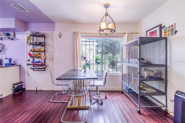 dining space with hardwood / wood-style floors and a notable chandelier