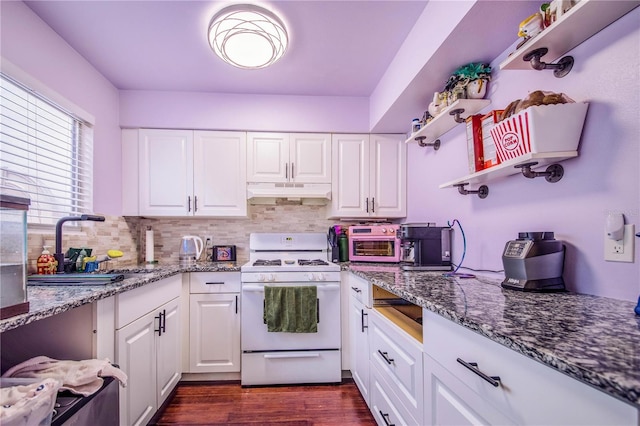 kitchen featuring white cabinets, decorative backsplash, white range with gas cooktop, and dark stone counters