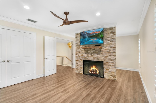 unfurnished living room featuring a fireplace, crown molding, wood-type flooring, and ceiling fan