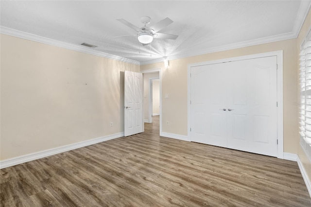 unfurnished bedroom with wood-type flooring, ornamental molding, ceiling fan, and a closet