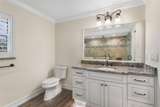 bathroom featuring hardwood / wood-style flooring, a shower with door, vanity, ornamental molding, and a textured ceiling