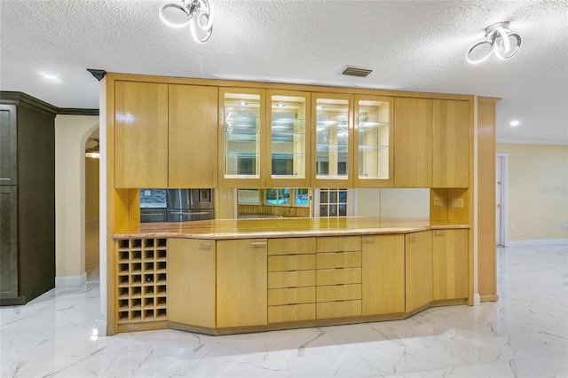 bar with stainless steel fridge, light brown cabinetry, and a textured ceiling