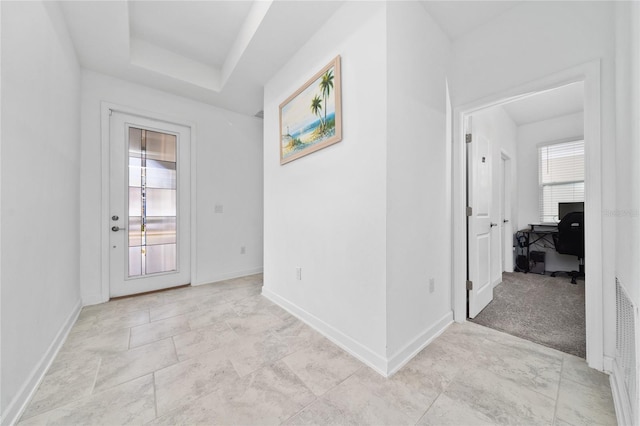 carpeted entryway with a tray ceiling