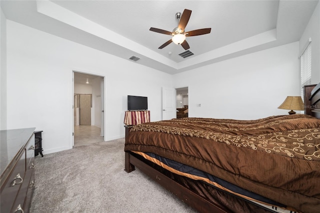 carpeted bedroom featuring ceiling fan and a raised ceiling