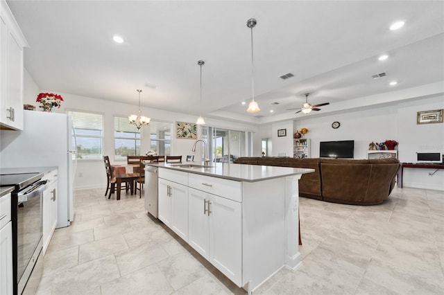 kitchen featuring white cabinets, ceiling fan with notable chandelier, sink, an island with sink, and appliances with stainless steel finishes