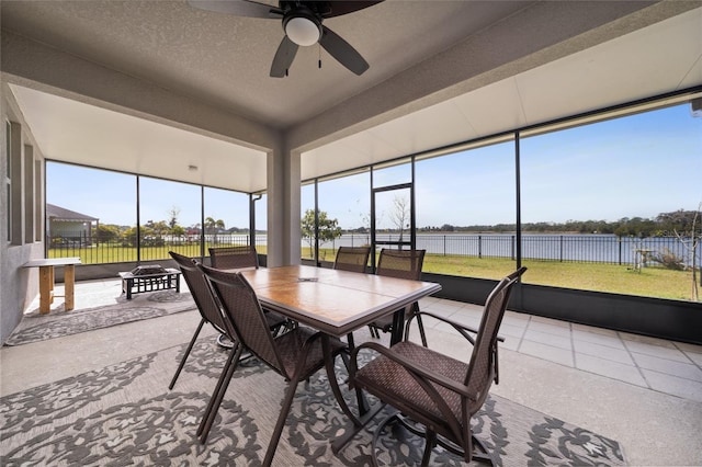 sunroom / solarium featuring ceiling fan and a water view