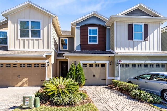 view of front of property featuring a garage, decorative driveway, board and batten siding, and a shingled roof