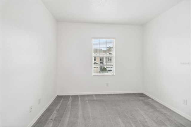 carpeted empty room featuring baseboards