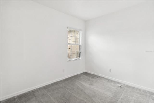 spare room featuring baseboards and light colored carpet