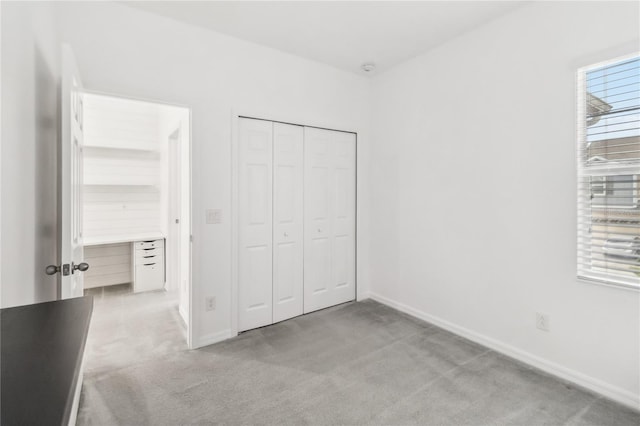 unfurnished bedroom featuring light carpet, a closet, and baseboards