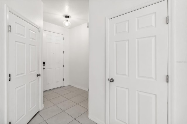 corridor with light tile patterned floors and baseboards