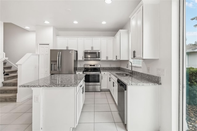 kitchen with light stone countertops, light tile patterned floors, appliances with stainless steel finishes, and a center island