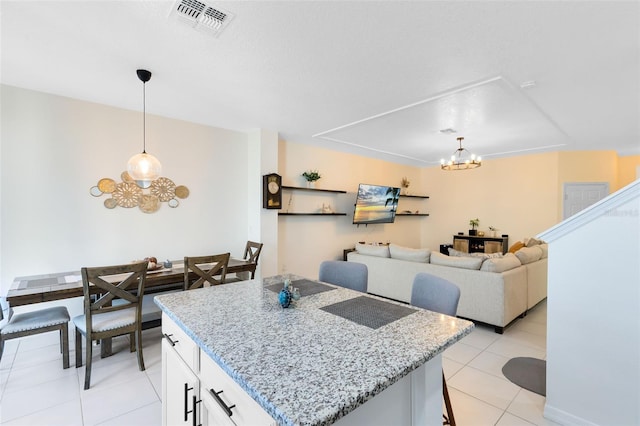 kitchen featuring light stone counters, visible vents, hanging light fixtures, white cabinetry, and a chandelier