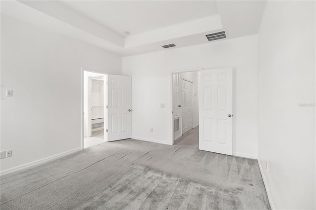 unfurnished bedroom featuring carpet floors, a raised ceiling, visible vents, and baseboards