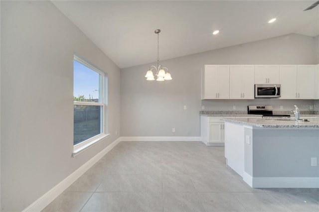 kitchen featuring light stone counters, stainless steel appliances, vaulted ceiling, pendant lighting, and white cabinetry