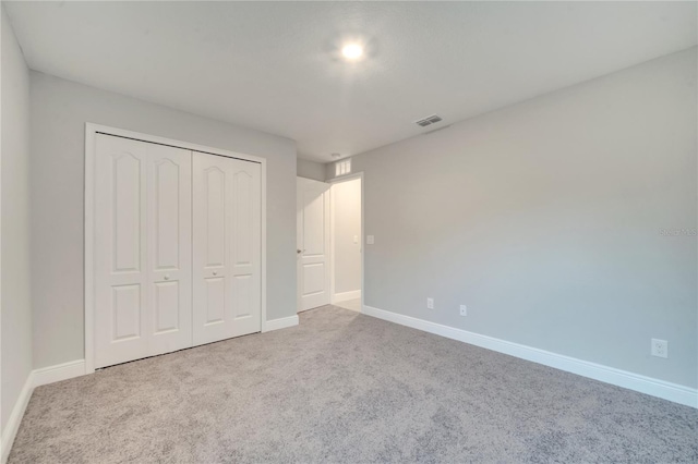 unfurnished bedroom with light carpet and a closet