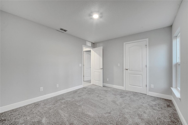 unfurnished bedroom with carpet flooring, multiple windows, and a textured ceiling