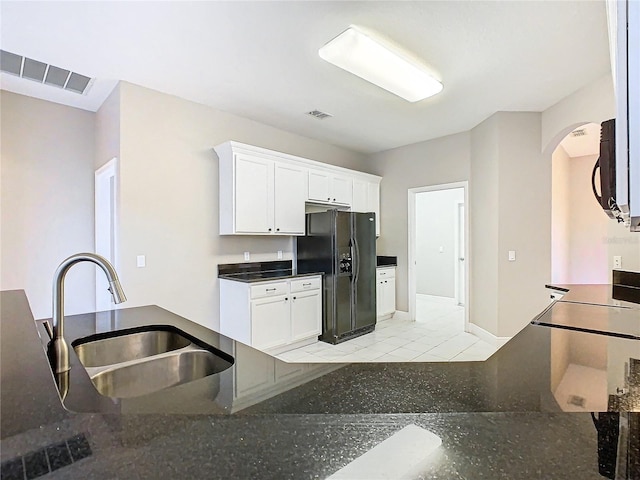 kitchen featuring black refrigerator with ice dispenser, sink, and white cabinetry