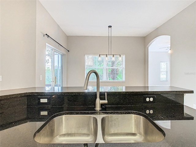 kitchen featuring sink, ceiling fan, pendant lighting, and dark stone counters