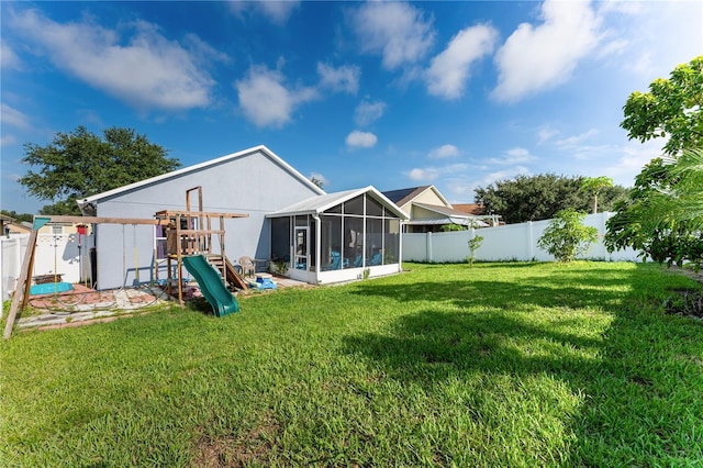 back of property with a sunroom, a playground, and a lawn