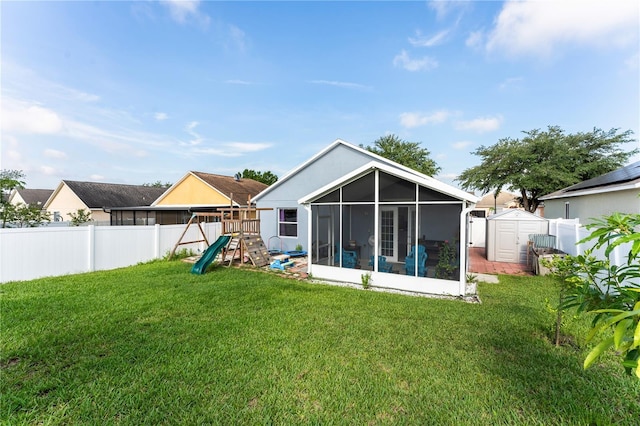 back of house with a playground, a yard, and a shed