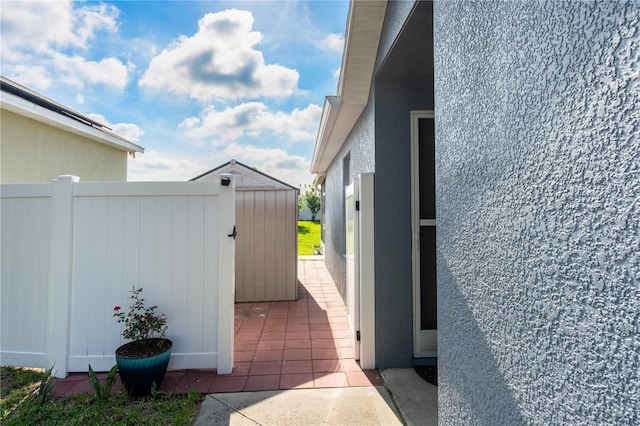 view of side of home featuring a patio and a shed