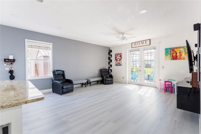 living area featuring french doors, light hardwood / wood-style floors, and ceiling fan