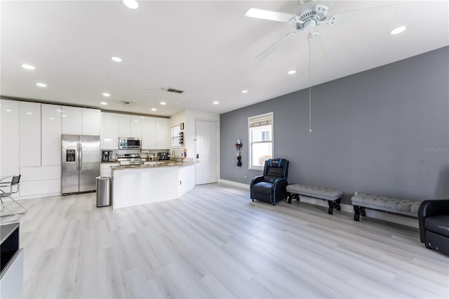 kitchen with white cabinets, appliances with stainless steel finishes, kitchen peninsula, and light hardwood / wood-style flooring