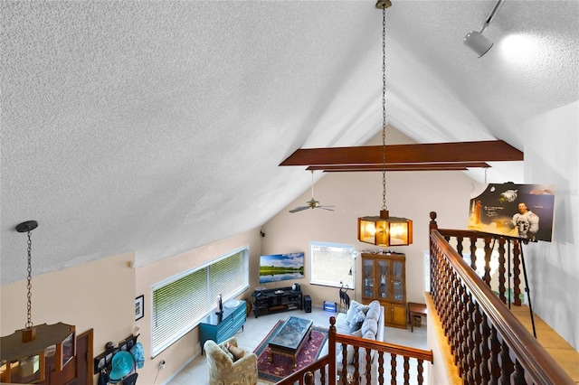 living room featuring ceiling fan with notable chandelier and vaulted ceiling with beams