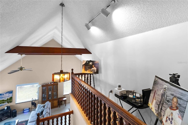 interior space featuring lofted ceiling with beams, track lighting, and a chandelier