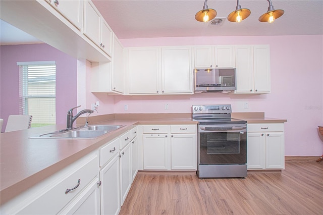 kitchen with sink, white cabinetry, hanging light fixtures, and appliances with stainless steel finishes