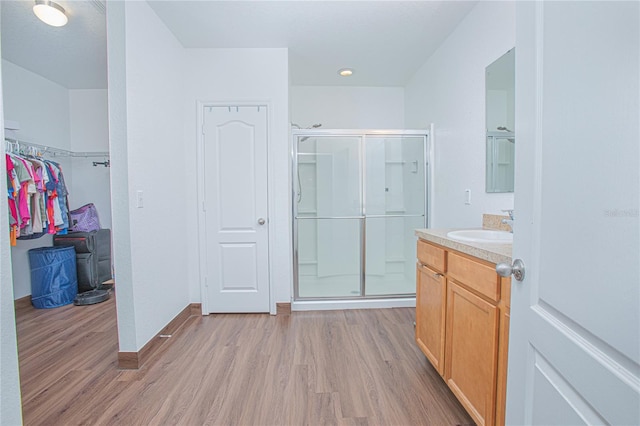 bathroom with hardwood / wood-style floors, vanity, and a shower with door