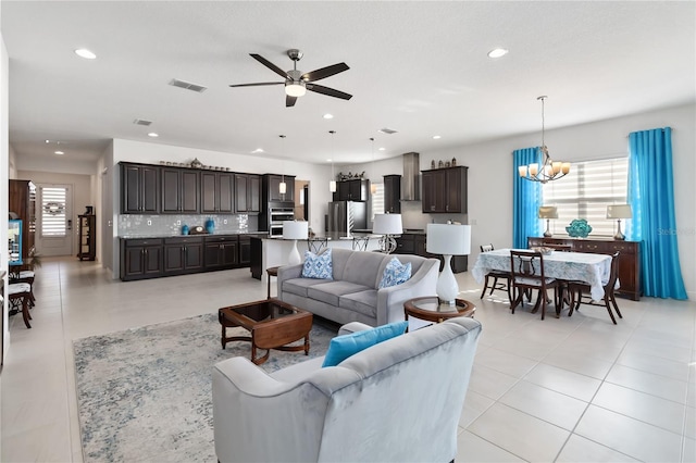 tiled living room with ceiling fan with notable chandelier and a wealth of natural light