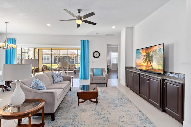 tiled living room with ceiling fan with notable chandelier