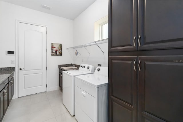 laundry room with sink, light tile patterned floors, cabinets, and independent washer and dryer