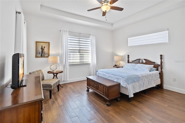 bedroom with ceiling fan, a raised ceiling, and wood-type flooring