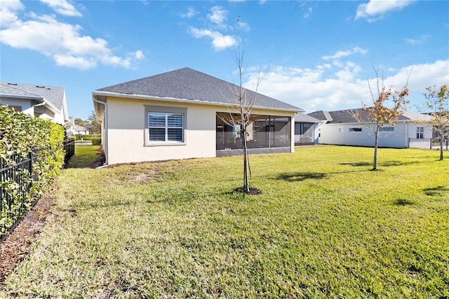 rear view of house featuring a yard and a sunroom