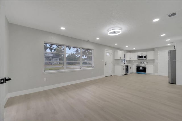 unfurnished living room with light wood-type flooring, a textured ceiling, and sink