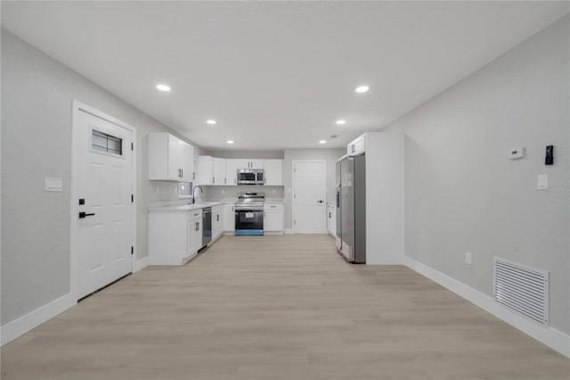 kitchen featuring sink, white cabinets, light hardwood / wood-style floors, and appliances with stainless steel finishes