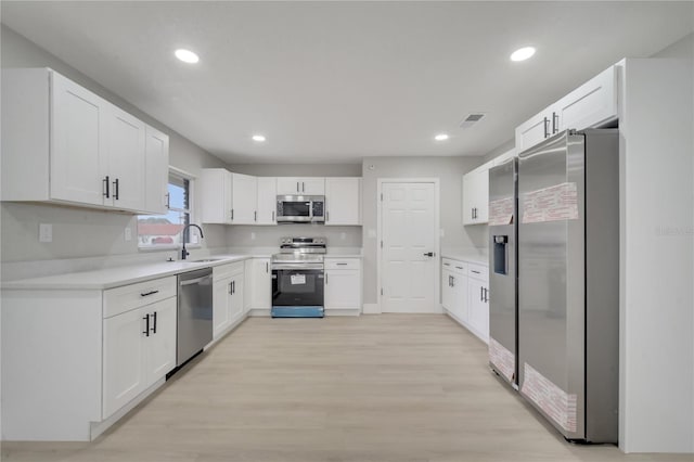 kitchen with sink, light hardwood / wood-style floors, white cabinetry, and stainless steel appliances